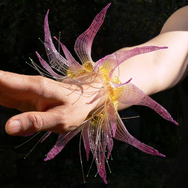 Aqualegia|The spirit of aqualegia 2004<br/>wrist piece<br/>woven dyed nylon<br/>diameter: 19cm / 7.5 inches<br/><br/>This unusual flower needs careful interpretation-a self sown plant that comes up year after year in our garden. The way I have woven it shows the marve pink bell shaped petals standing proudly against the neighbouring flowering lavender.